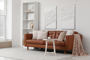Brown leather sofa with white table and shelving unit in living room