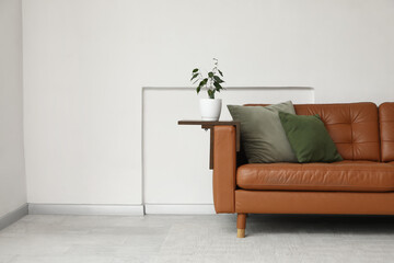 Brown leather sofa near white wall in room