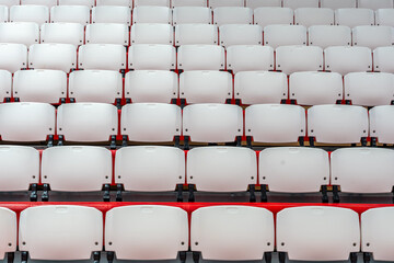 Close-up image of red and white plastic folding bleacher seats in an interior gymnasium.
