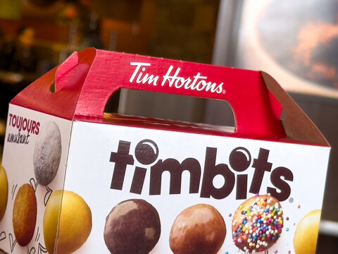 Calgary, Alberta, Canada. Apr 24, 2025. A close-up shot of a red and white Tim Hortons Timbits box, showcasing various donut holes with different toppings. The box features the "Tim Hortons" logo