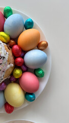 Colorful assortment of decorative Easter eggs arranged around a sweet cake on a white plate creating a festive atmosphere for spring celebrations and holiday gatherings concept