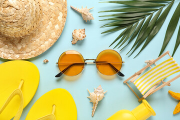 Hat with flip flops, sunglasses and palm leaf on blue background