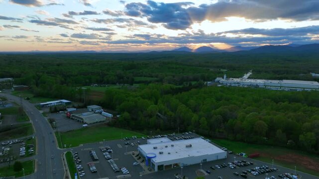 Hyperlapse of american Suburb intersection with traffic during Sunset. Parking cars at store and car dealership in Virginia, USA. Aerial wide shot. Fumes of factory rising into sky.