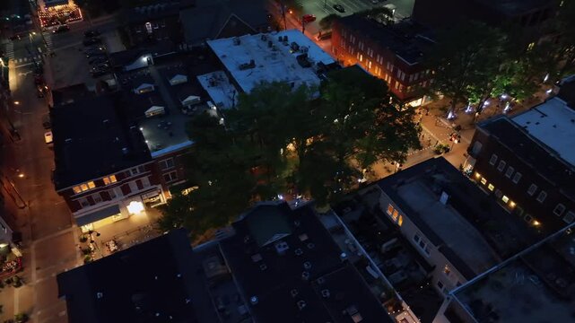 Illuminated shopping street in american town at night. Aerial top down shot. Walking people and pedestrian on road with lantern in Charlottesville, Virginia. Buildings and apartments in USA.