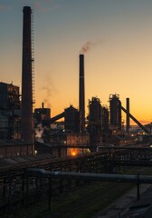 Naklejka premium Silhouetted Industrial Complex at Sunset