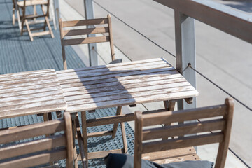 Wooden chairs and table on a sunny outdoor deck in mid-afternoon