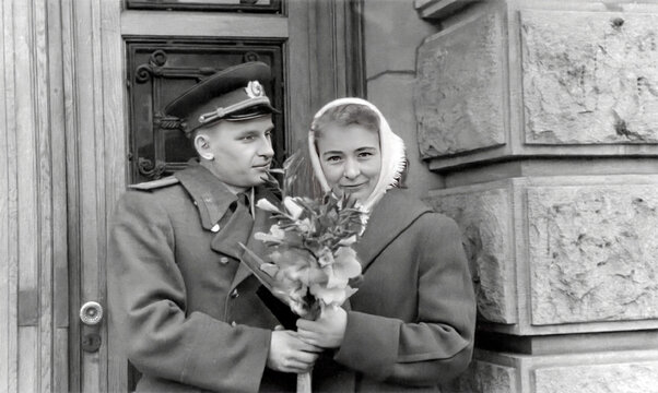 Retro portrait of a young military man giving flowers to a young woman. Vintage photo of a young family. February 1960.