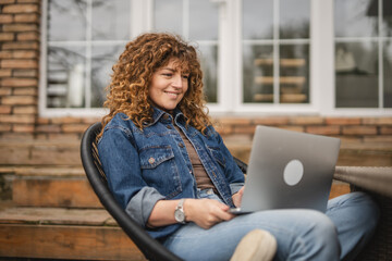 confident adult woman sit at garden and use laptop for explore