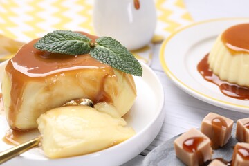 Delicious pudding with caramel sauce and mint served on light table, closeup