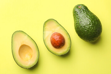 Whole and cut avocados on light green background, flat lay