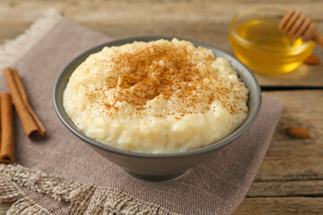 Delicious rice pudding with cinnamon, honey and almonds on wooden table, closeup