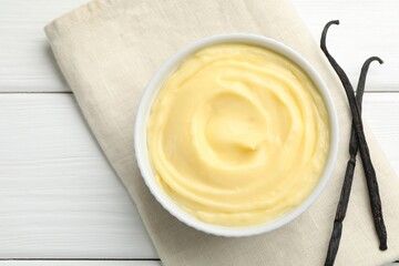 Tasty vanilla pudding and pods on white wooden table, top view