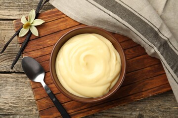 Tasty vanilla pudding, pods and flower on wooden table, flat lay