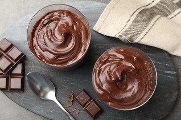 Tasty pudding and pieces of chocolate on grey table, flat lay