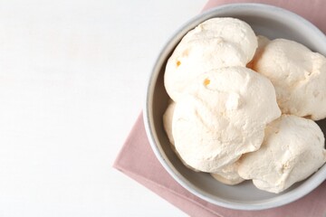 Delicious homemade meringue cookies in bowl on light table, top view. Space for text