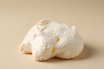 Delicious homemade meringue cookie on beige background, closeup