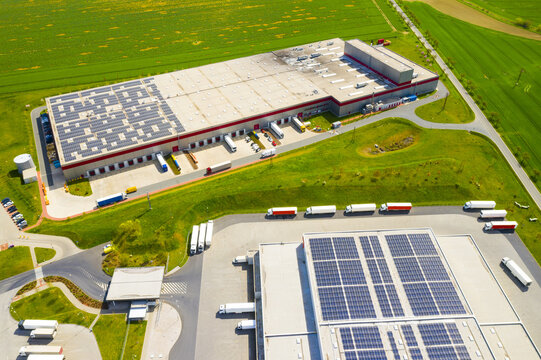 Industry with low carbon footprint. Industrial warehouses with solar panels on the roof. Technology park and factories from above
