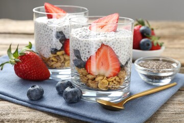 Delicious dessert with chia seeds, yogurt, granola, strawberries and blueberries on wooden table, closeup. Superfood