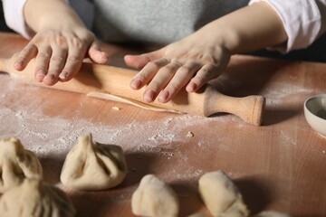 Obraz premium Woman making khinkali on table in kitchen, closeup