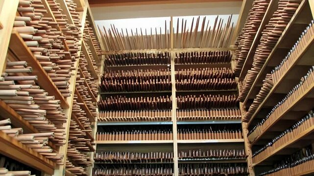 Storage shelves holding large quantity of wooden oboe parts and components in a workshop during instrument manufacturing.