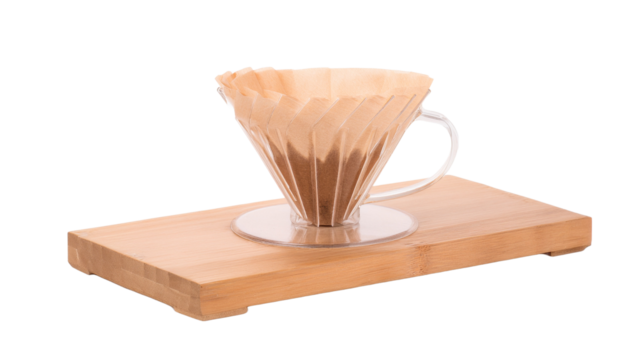 a close-up shot of coffee brewing using the pour-over method. The coffee setup includes a glass cup resting on a wooden surface. The coffee is brewing and it gives us a sense of the coffee aroma