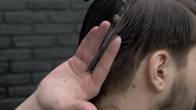 Barber skillfully sections lock of hair between his fingers and trims ends with precision scissors, refreshing brunette man s haircut.