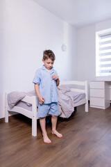 A little schoolboy is putting on a blue shirt to wear quickly gets dressed for school in the...