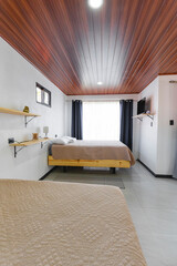 Minimalist bedroom with two beige beds, wooden ceiling and natural light