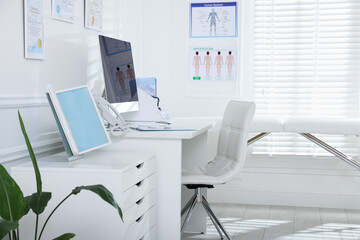 Doctor's workplace with modern computer and examination table in medical office