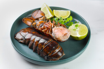 Raw lobster tails, lime and microgreens on white table, closeup
