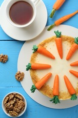Delicious homemade carrot cake served on light blue wooden table, flat lay