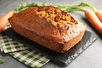 Tasty carrot cake and vegetables on grey textured table, closeup