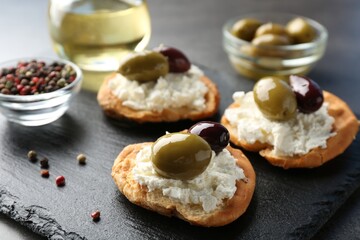 Delicious sandwiches with marinated olives, cream cheese and peppercorns on dark table, closeup