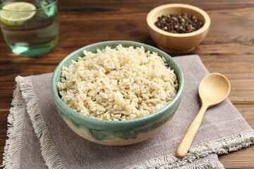 Delicious brown rice served on wooden table, closeup