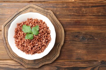Delicious brown rice with parsley served on wooden table, top view. Space for text