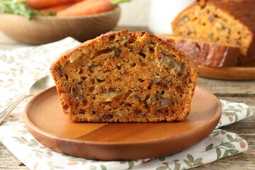 Cut homemade carrot cake with nuts and spoon on wooden table, closeup