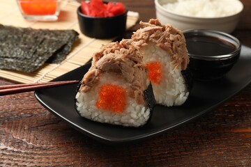 Tasty onigiri (Japanese rice balls) with tuna served on wooden table, closeup