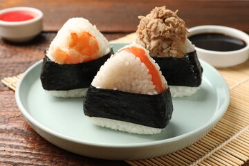 Tasty onigiri (Japanese rice balls) served on wooden table, closeup