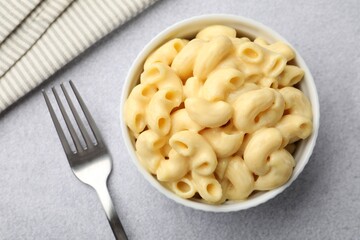 Delicious pasta with cheese sauce and fork on grey table, flat lay