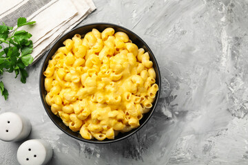 Delicious pasta with cheese sauce in bowl and parsley on grey table, flat lay. Space for text