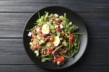 Delicious salad with brown rice on black wooden table, top view