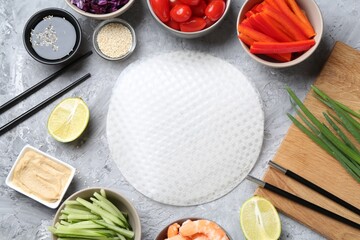 Rice paper sheets and different ingredients on light grey table, flat lay