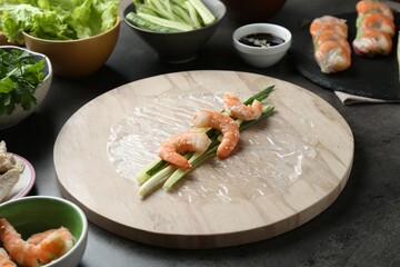 Rice paper sheets and different ingredients on dark grey table, closeup