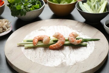 Rice paper sheets and different ingredients on dark grey table, closeup