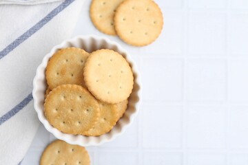 Tasty salty crackers on white tiled table, flat lay. Space for text
