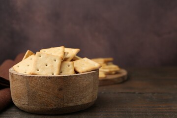 Tasty salty crackers on wooden table. Space for text