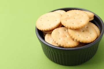 Tasty salty crackers on green background, closeup