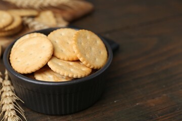 Tasty salty crackers and wheat spikes on wooden table, closeup. Space for text