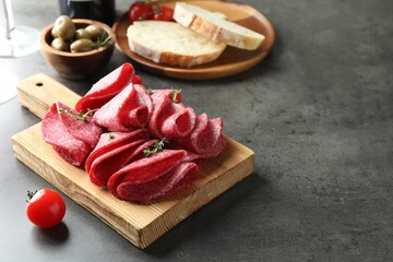 Slices of delicious sausage with thyme served on grey table. Space for text