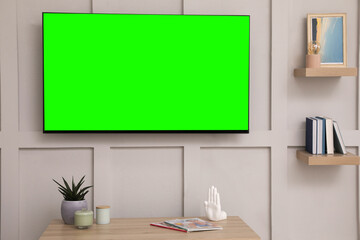 TV set with green screen on white wall in room. Chroma key compositing